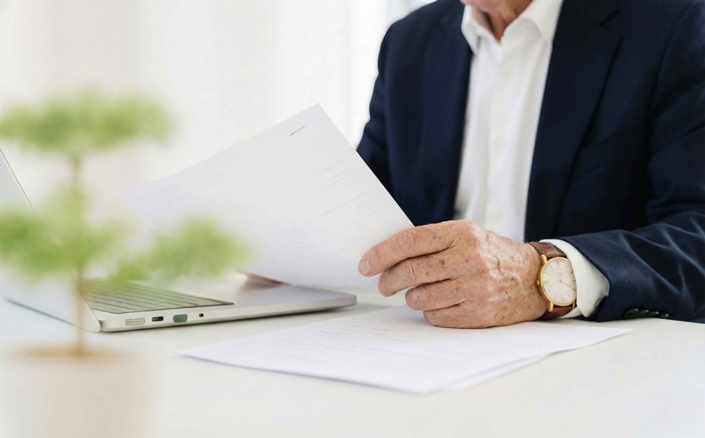 Geschäftsmann prüft Unterlagen vor Laptop – Immobilienberatung in Dresden