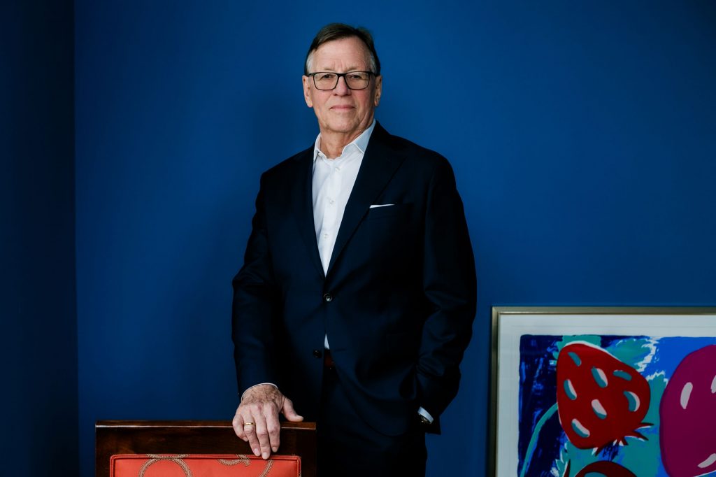 Detlef Trenner steht vor blauem Hintergrund und Kunstwerk, Immobilienexperte in Dresden