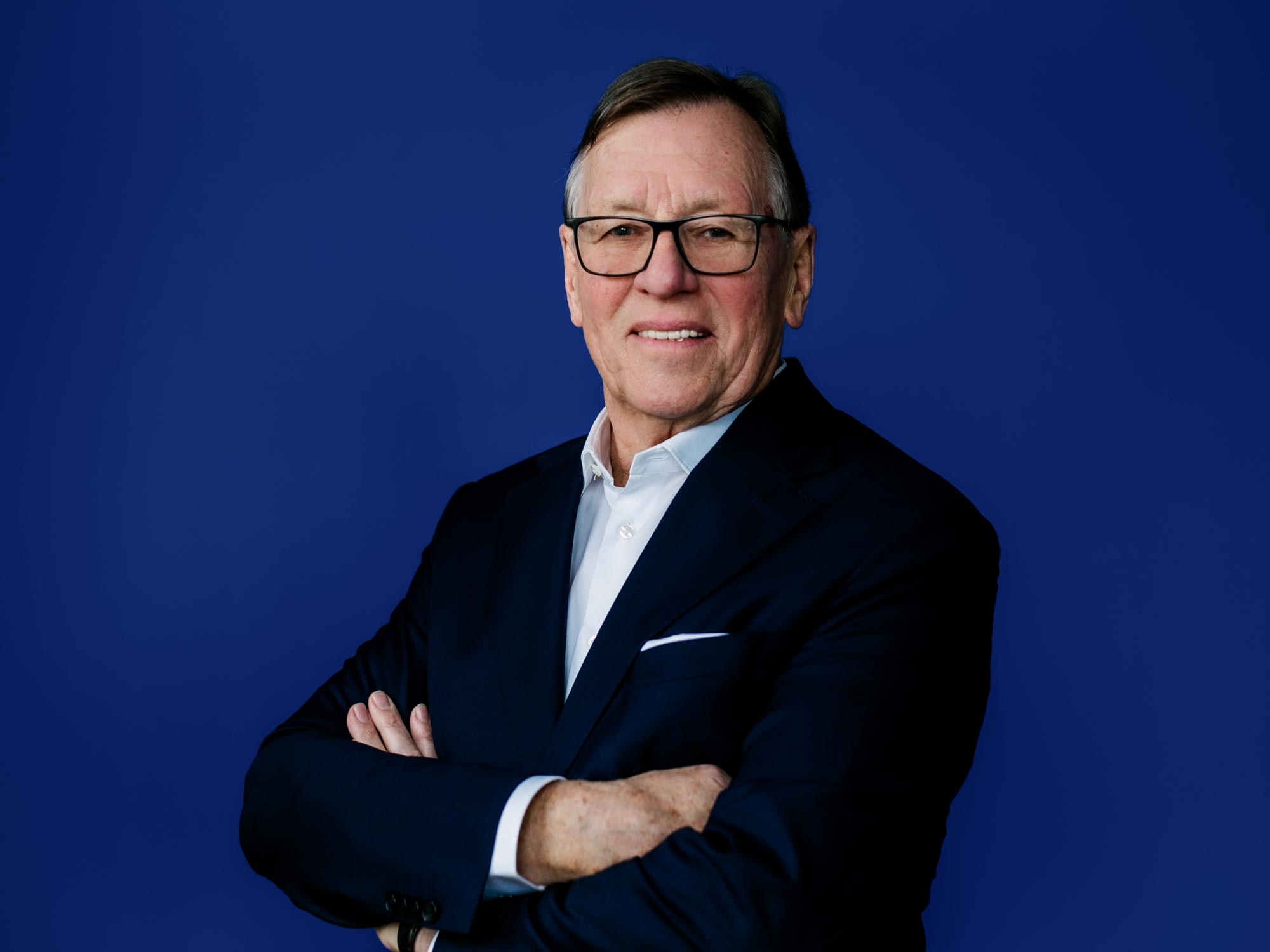 Porträt von Detlef Trenner mit verschränkten Armen vor blauem Hintergrund, Immobilienexperte in Dresden